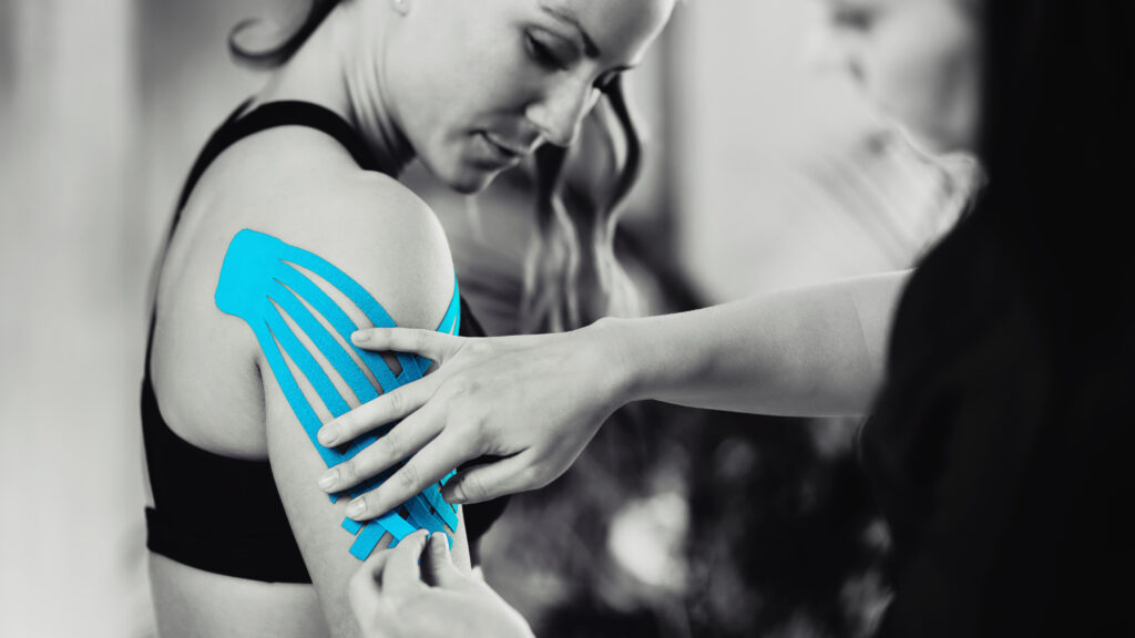 Black and white image of kinesiology taping treatment with blue tape on female patient injured arm. Sports injury kinesio treatment.